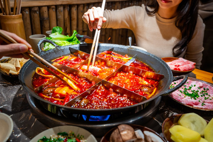 Mujer comiendo el platillo tradicional Chino en Chongqin HotPot